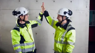 Kaksi työkaverusta kädet ylhäällä