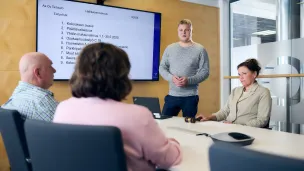 Neljä ihmistä kokoustilassa kokouksessa