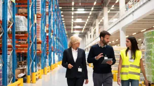 ihmisiä kävelee korkeavaraston käytävällä