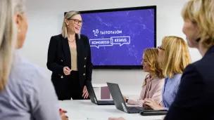 Professional meeting with a presentation screen and five people engaging.